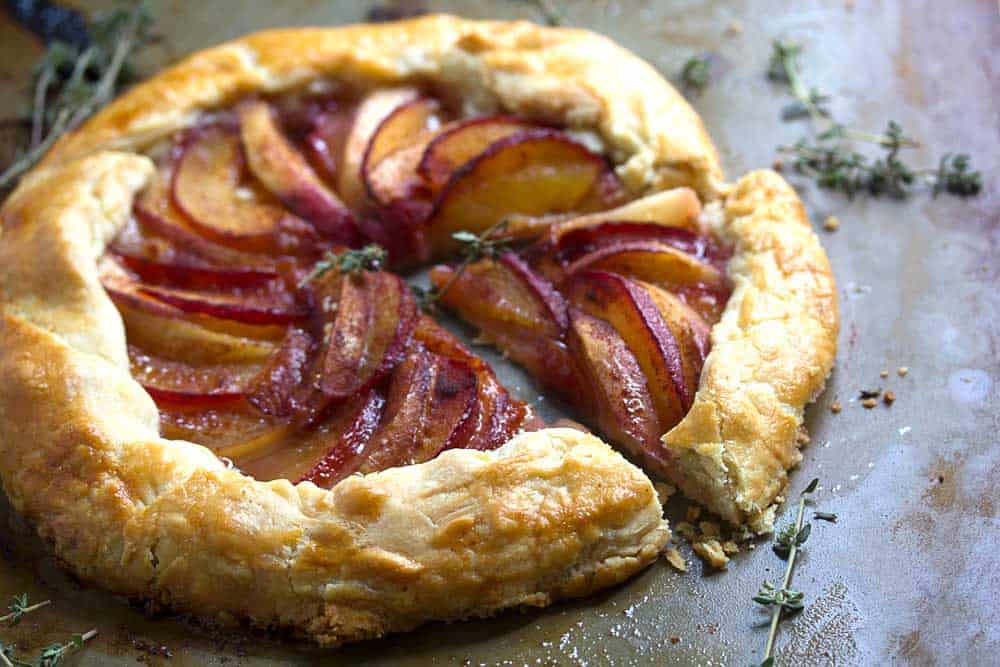 A plum necatrine galette with a slice cut out of it 