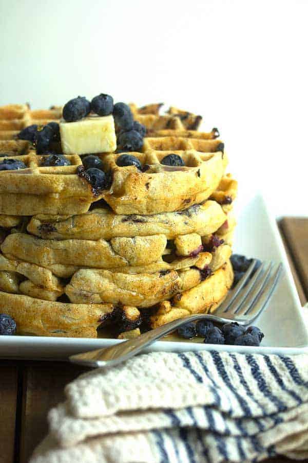 A stack of buttermilk Belgian blueberry waffles with butter and syrup