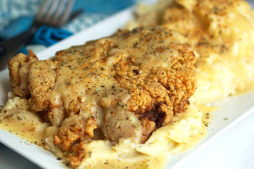 One of the best Chicken Fried Steaks on a plate with mashed potatoes and gravy