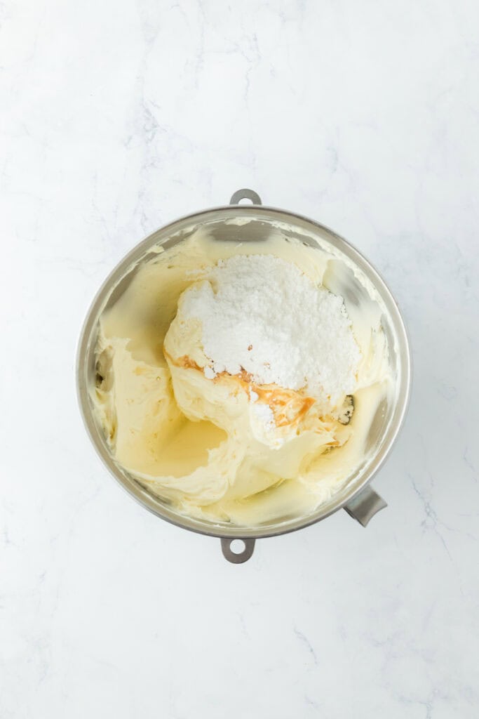 Powdered sugar added to stand mixer on white countertop