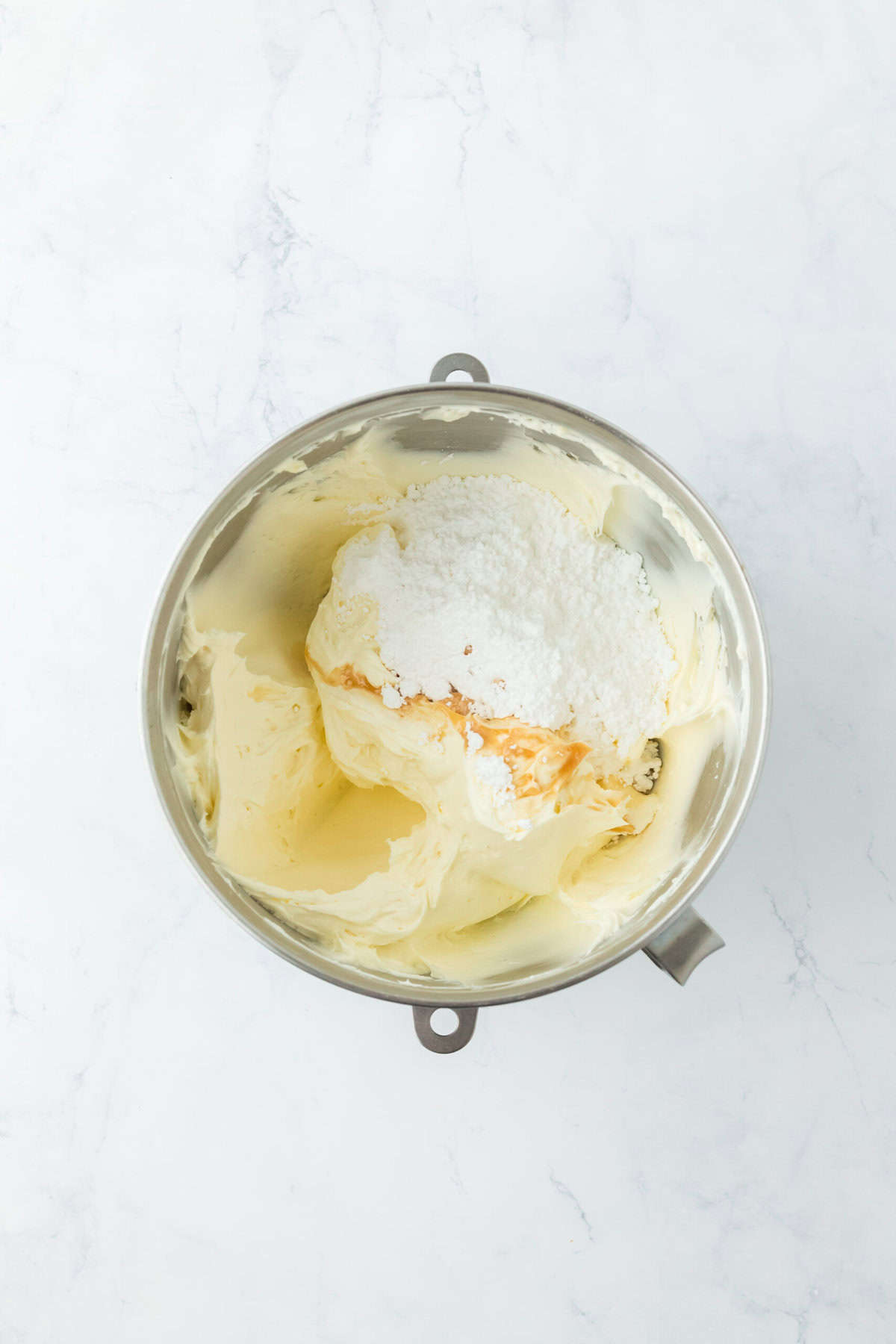 Powdered sugar added to stand mixer on white countertop