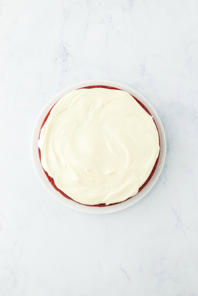 Frosting added to cake layers on white countertop