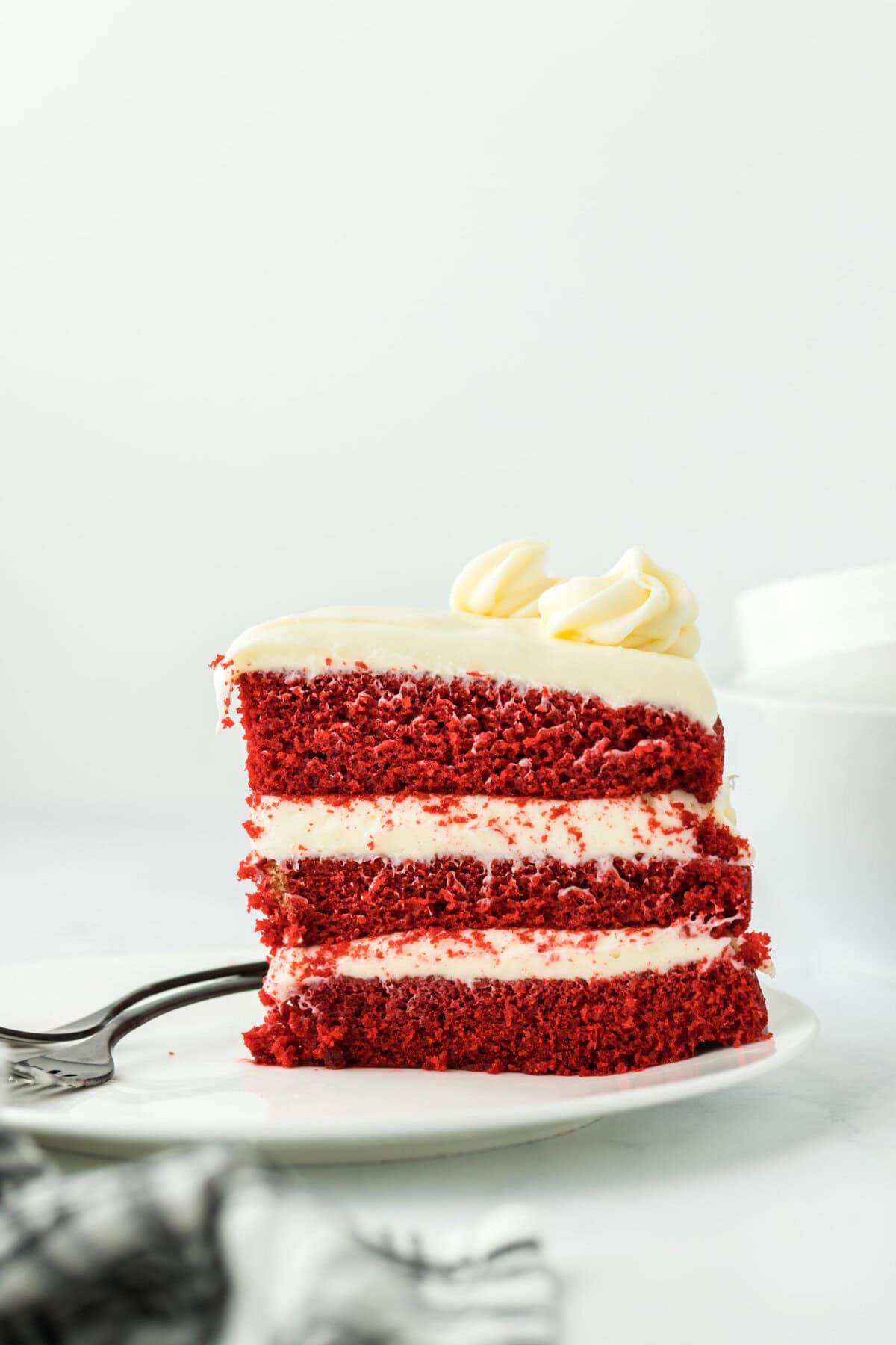 A slice of red velvet cake on white plate in white background