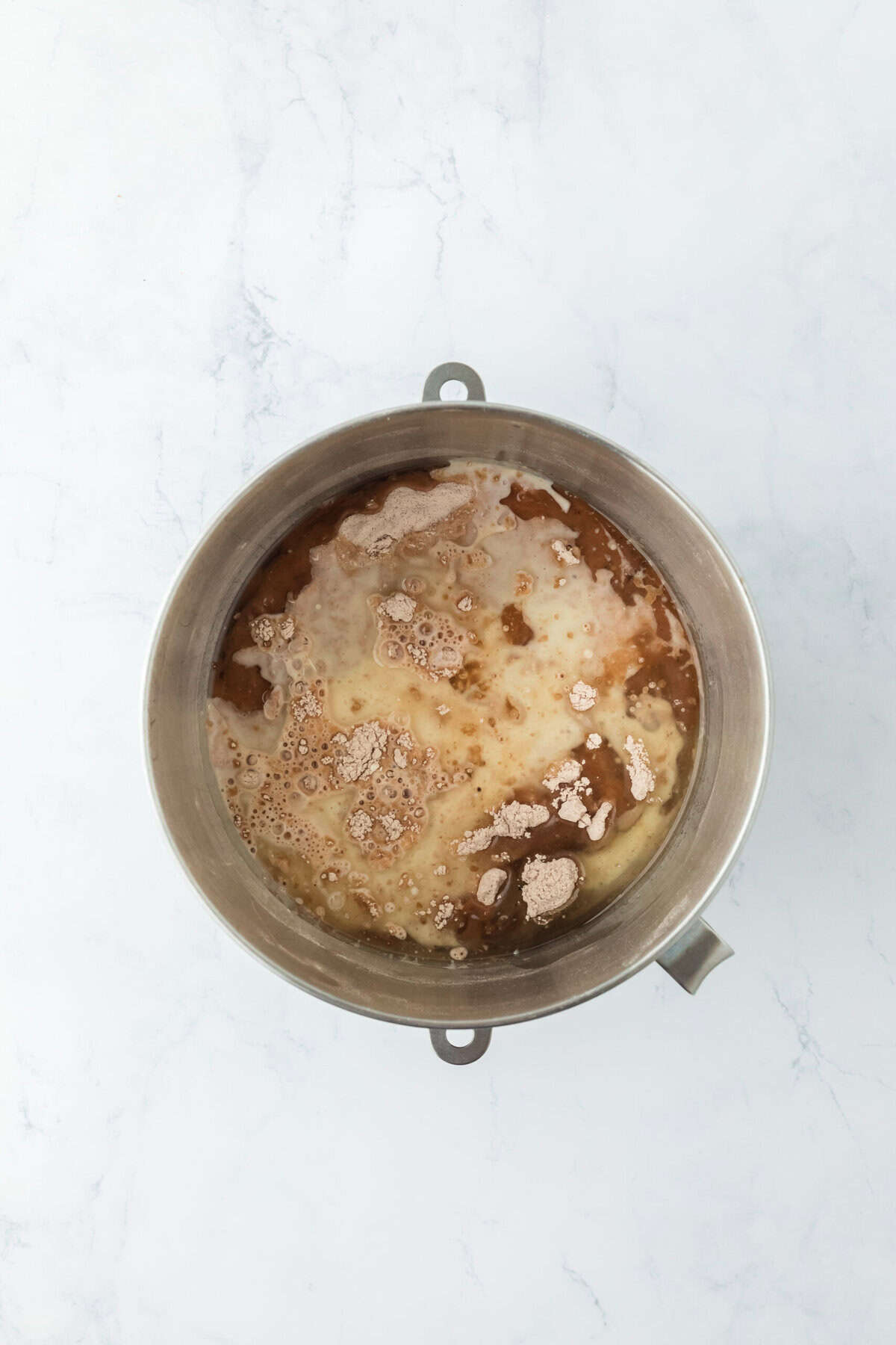 Oil and buttermilk added to a cake mixture in stand mixer on white countertop