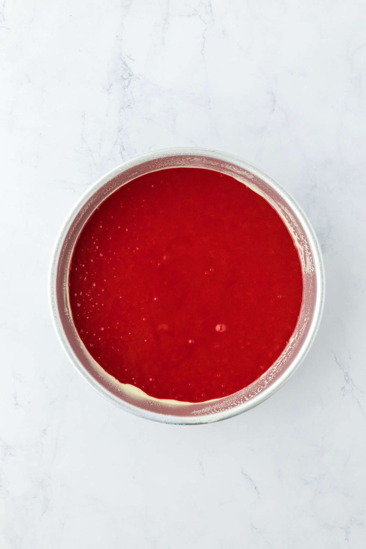 Red velvet cake batter in prepared cake pans before baking