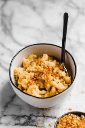 A large white bowl of Slow Cooker Macaroni and Cheese recipe with fork ready to eat against white background