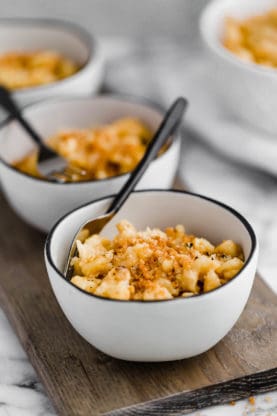 Several white bowls of lined up Slow Cooker Mac and Cheese recipe ready to serve (Slow Cooker Mac N Cheese)