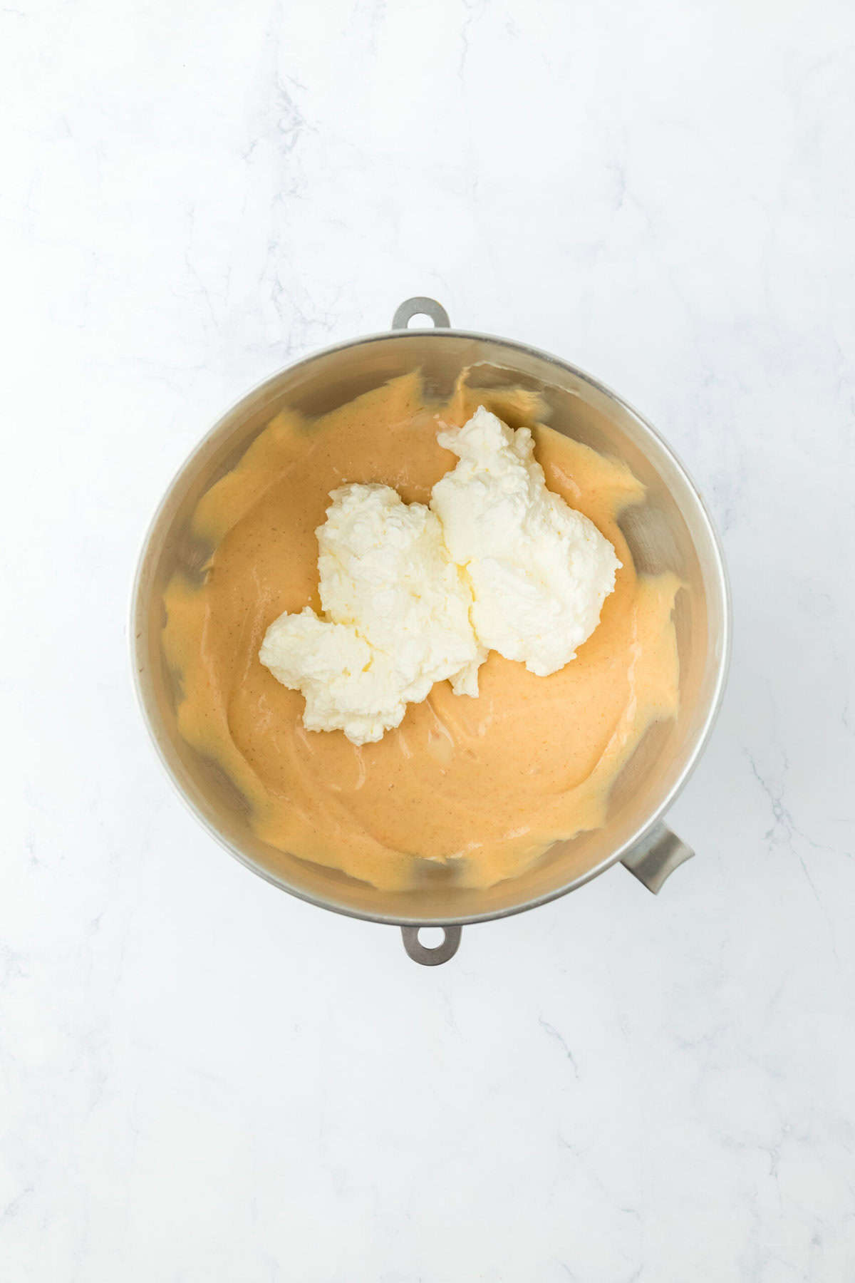 Whipped cream folding into no churn sweet potato ice cream base on white countertop