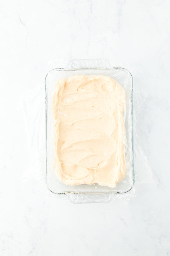 Half of sweet potato ice cream base into lined container on white countertop