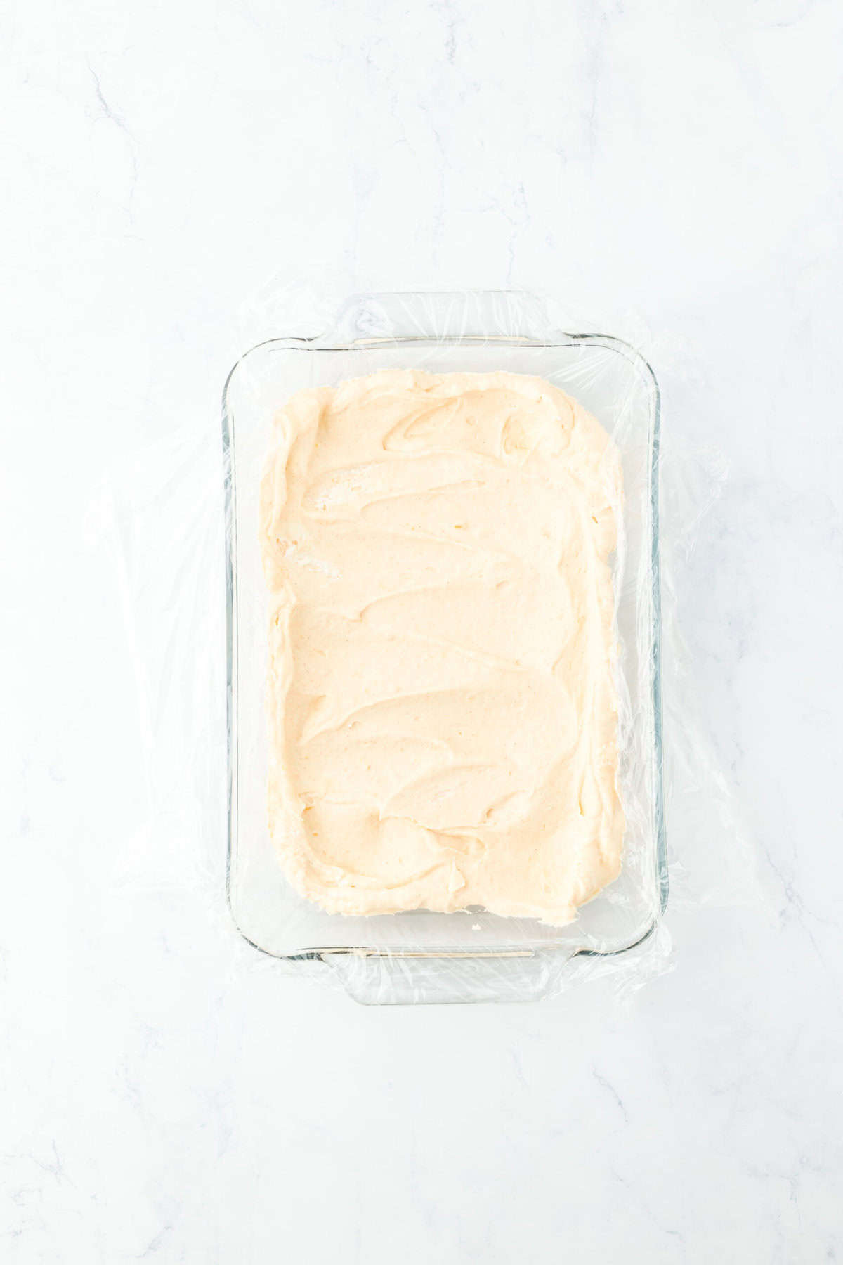 Half of sweet potato ice cream base into lined container on white countertop