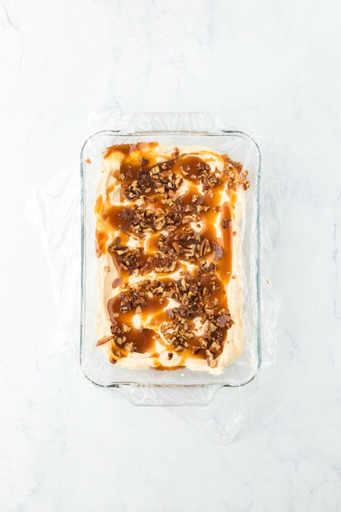Caramel and buttered pecans swirled in sweet potato ice cream base on white countertop