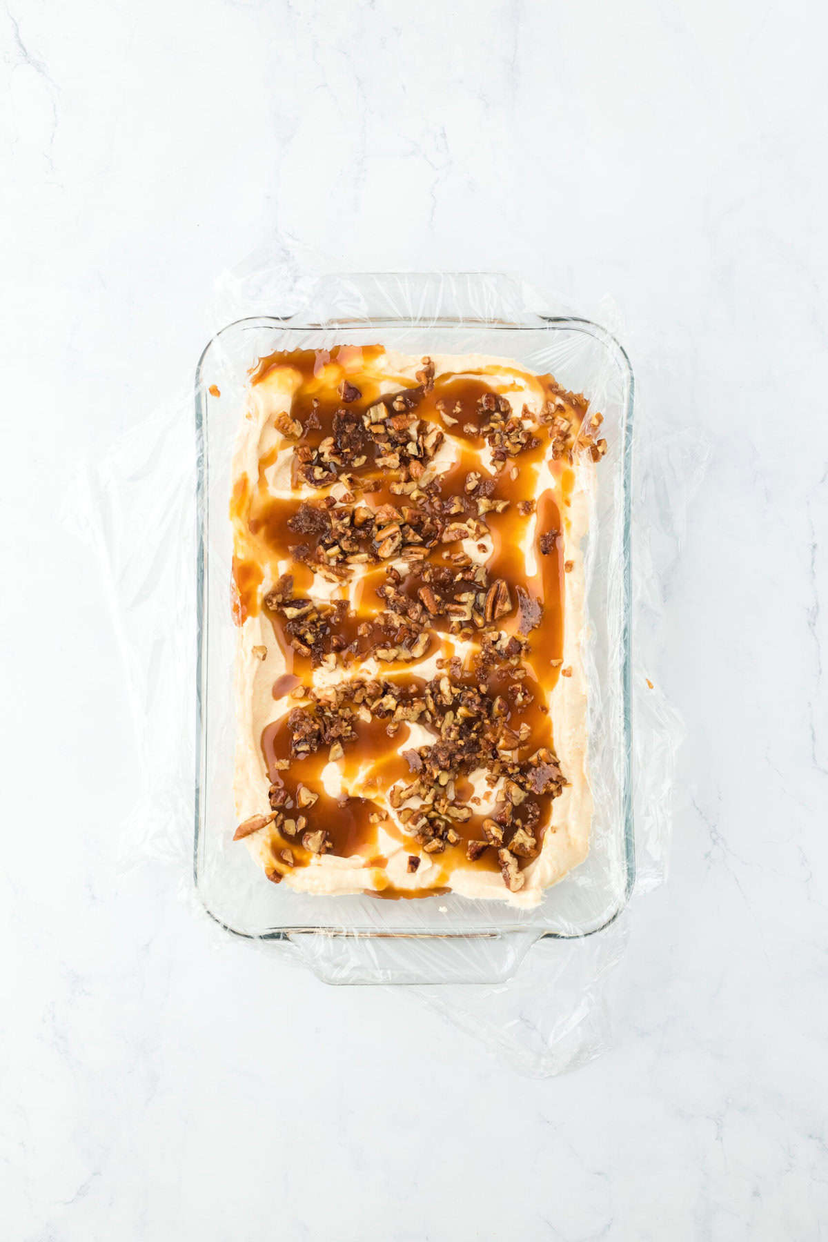 Caramel and buttered pecans swirled in sweet potato ice cream base on white countertop