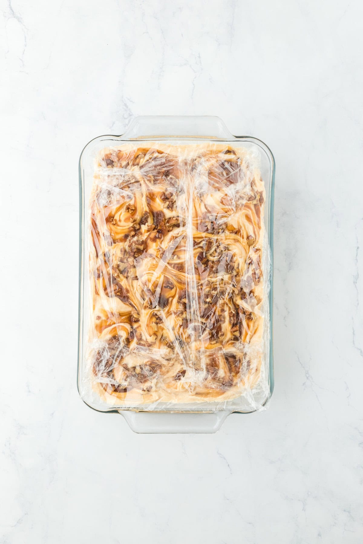 Sweet potato ice cream swirled and ready to freeze with plastic on top.