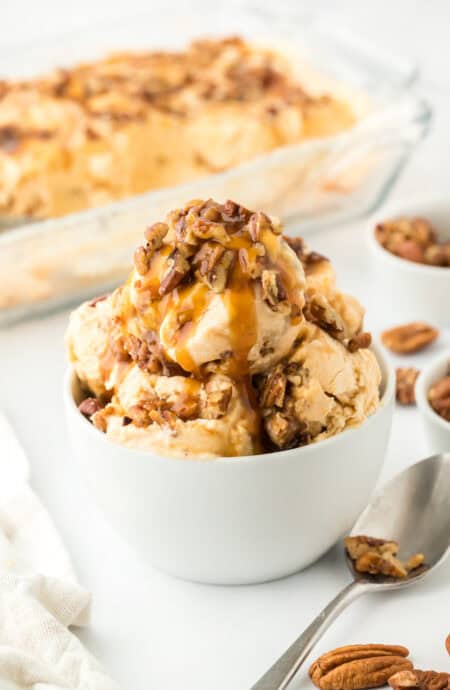 Sweet potato ice cream in a white bowl with carton of ice cream in white background