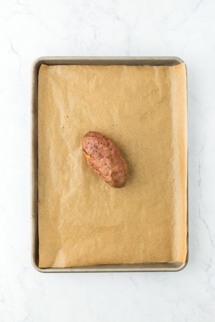 Baked sweet potato on a parchment lined baking sheet