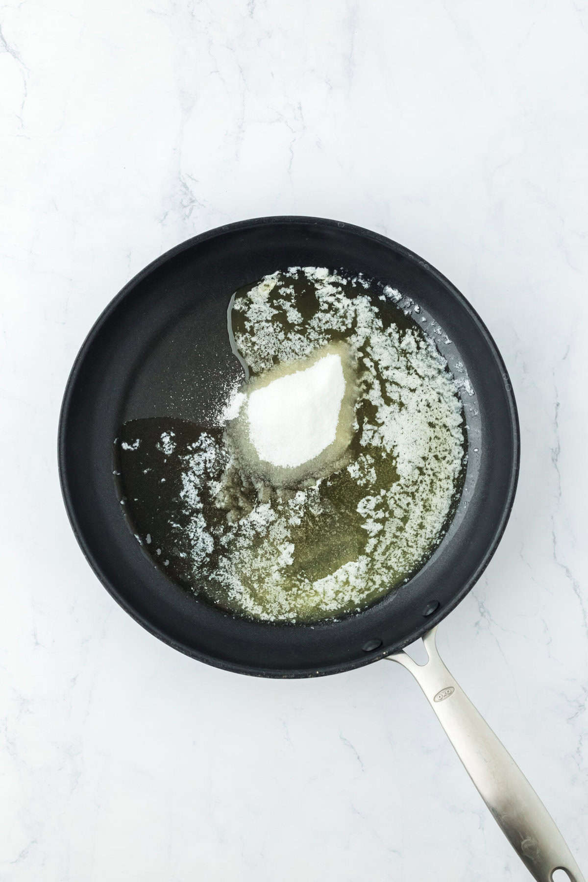 Butter melted in a skillet on white countertop.