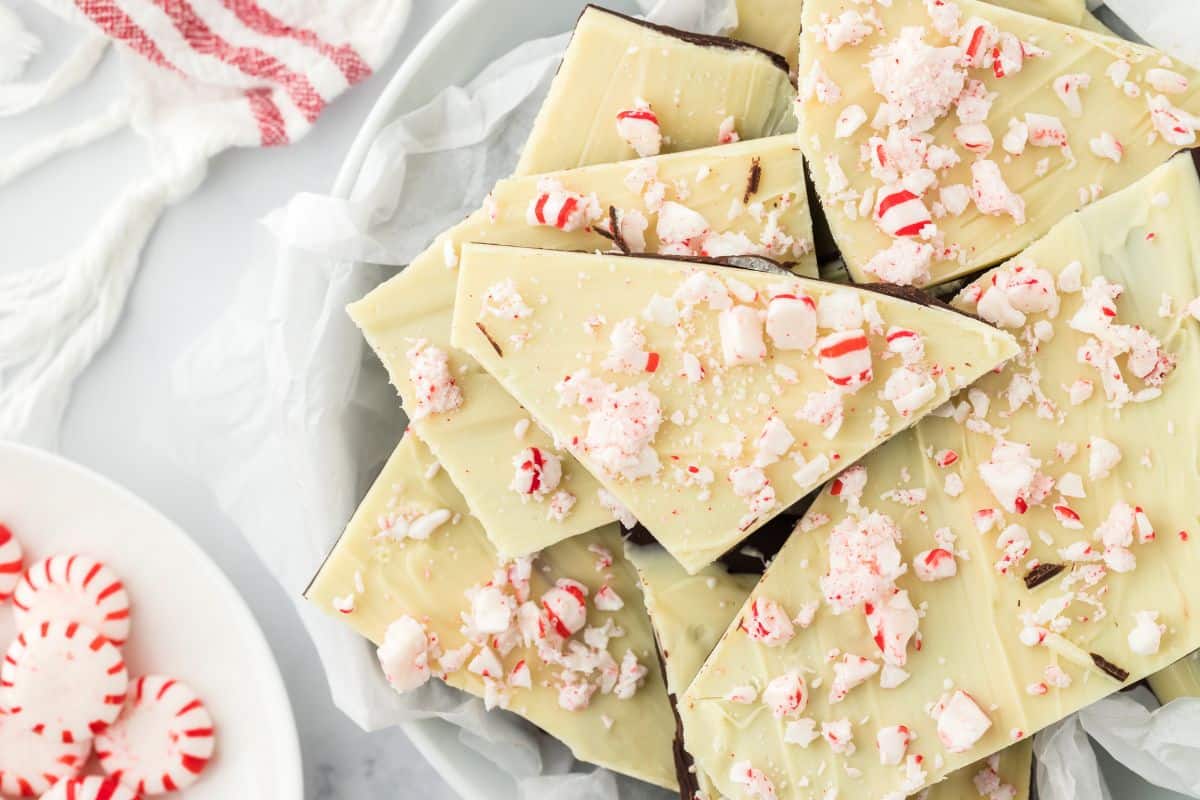 Peppermint bark on a plate with a dish of peppermint candies in the corner.