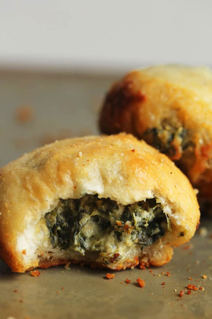 Close up of two Spinach Dip Stuffed Garlic Rolls with one with a bite taken out of it