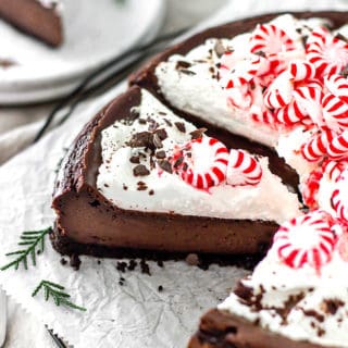 Chocolate peppermint cheesecake on white parchment with slices missing