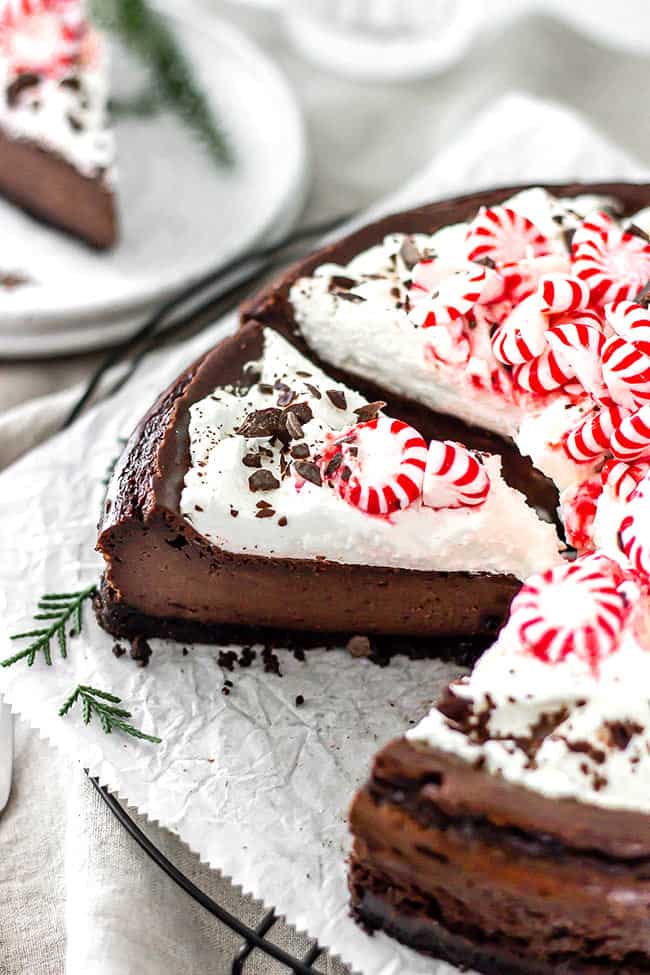 Chocolate peppermint cheesecake on white parchment with slices missing