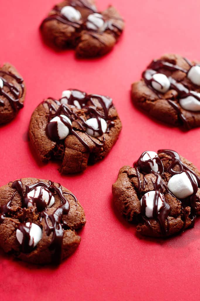Mud Cookies topped with marshmallows and drizzled chocolate sauce.