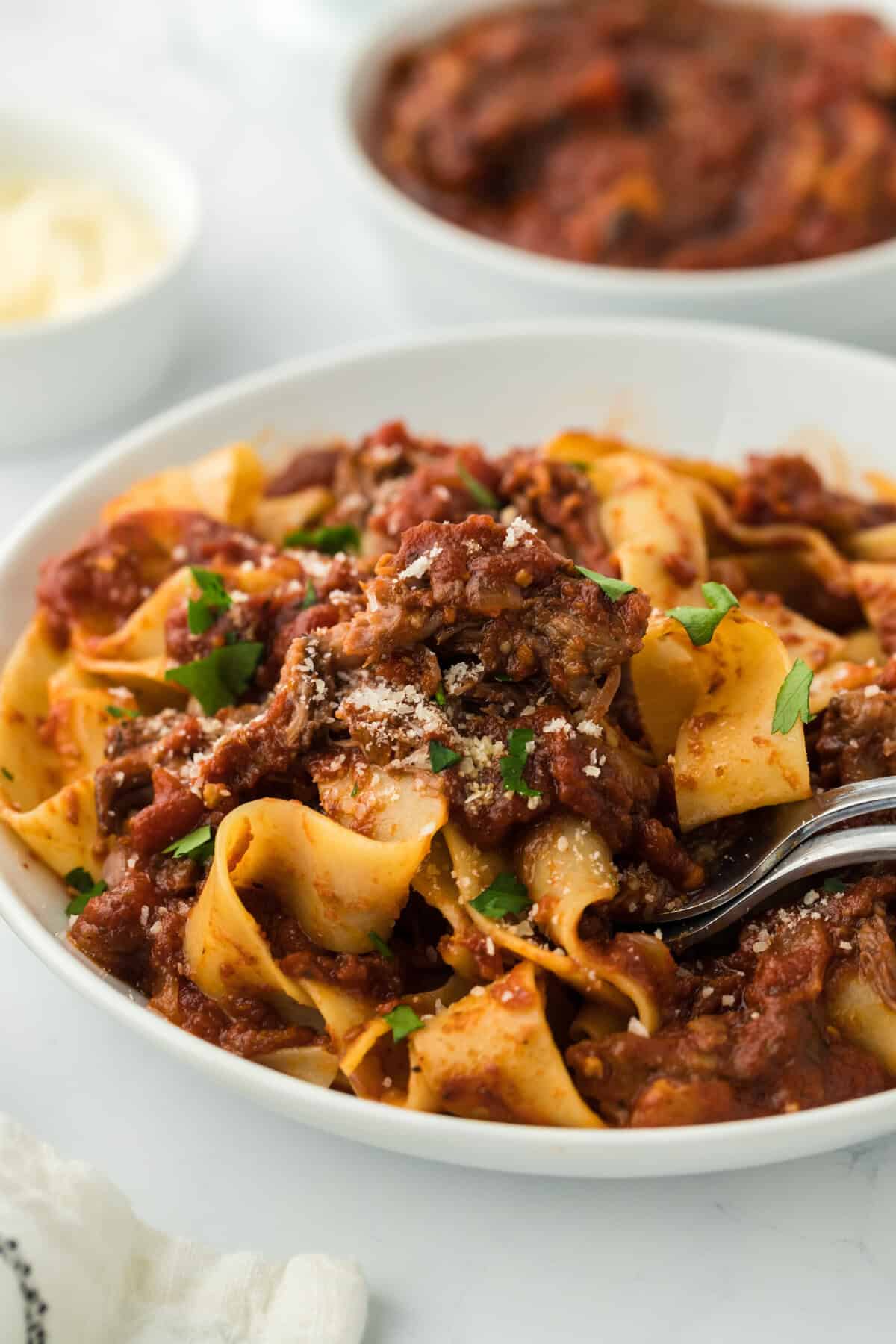 Beef ragu on white plate with fork ready to enjoy