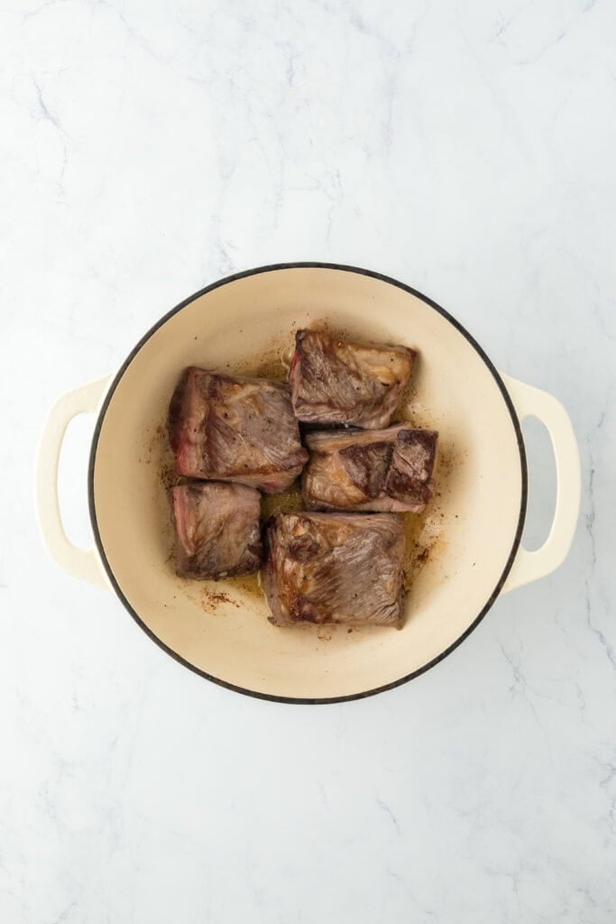 Short ribs browning in a hot pot on white countertop
