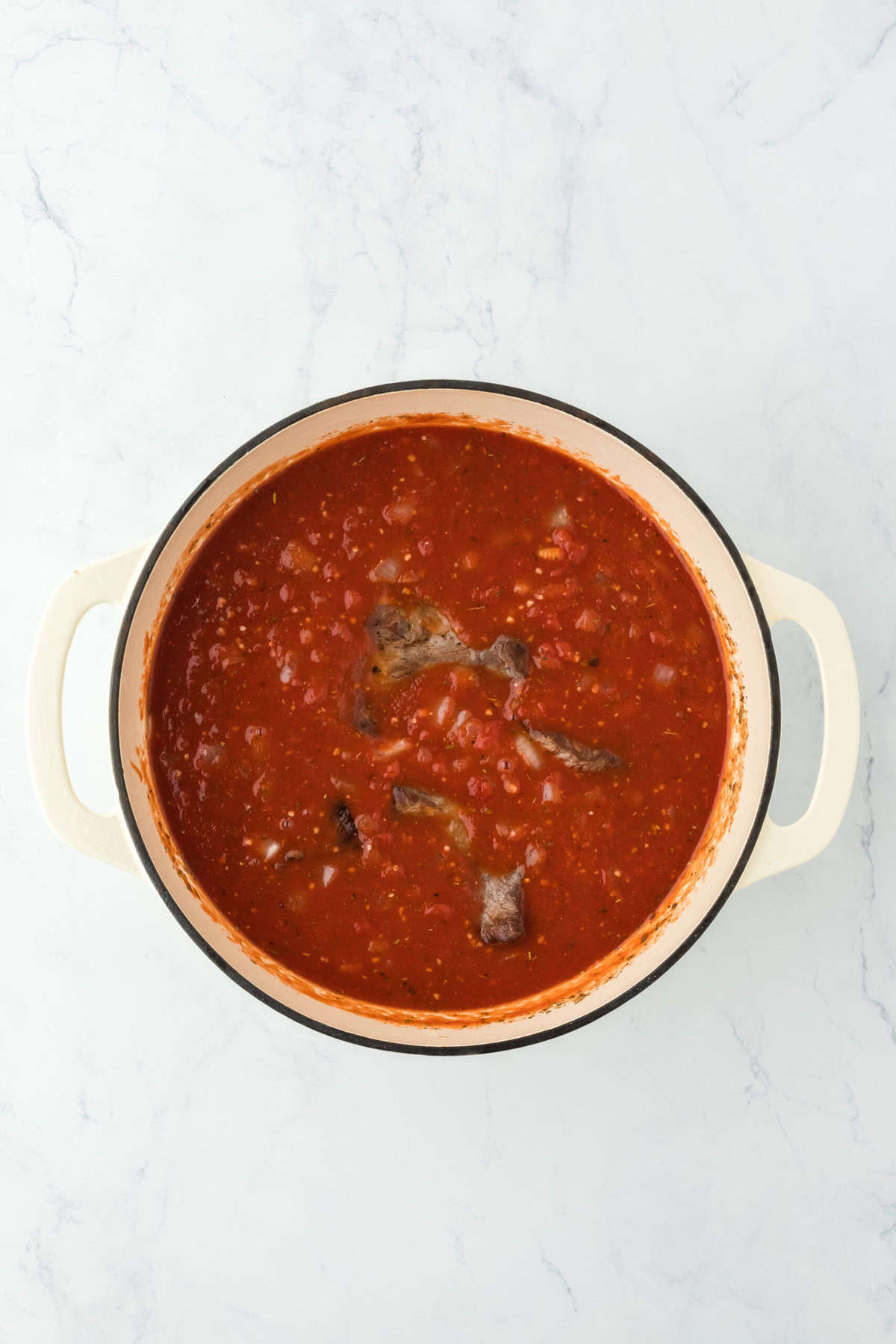 Short ribs added back into ragu sauce in a large dutch oven