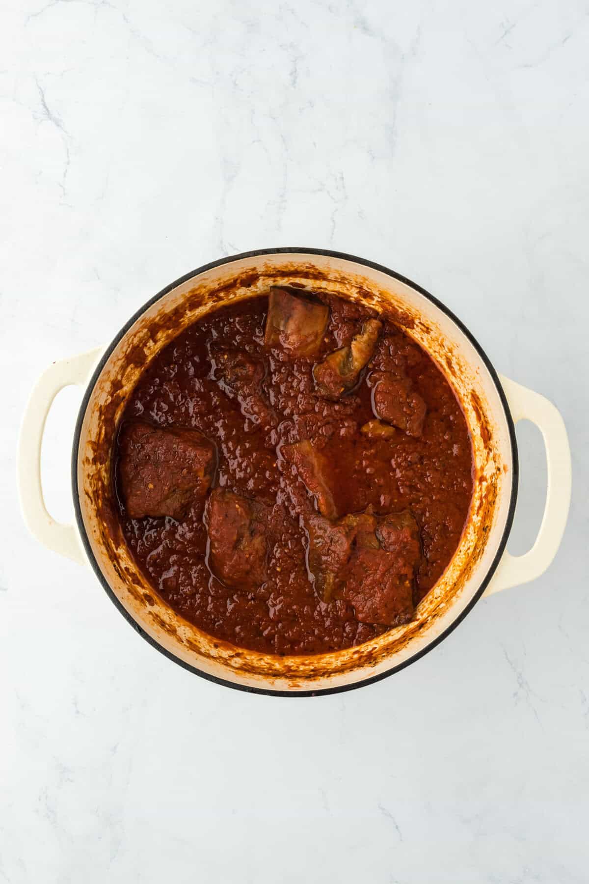 Baked short rib ragu in a large dutch oven on a white countertop