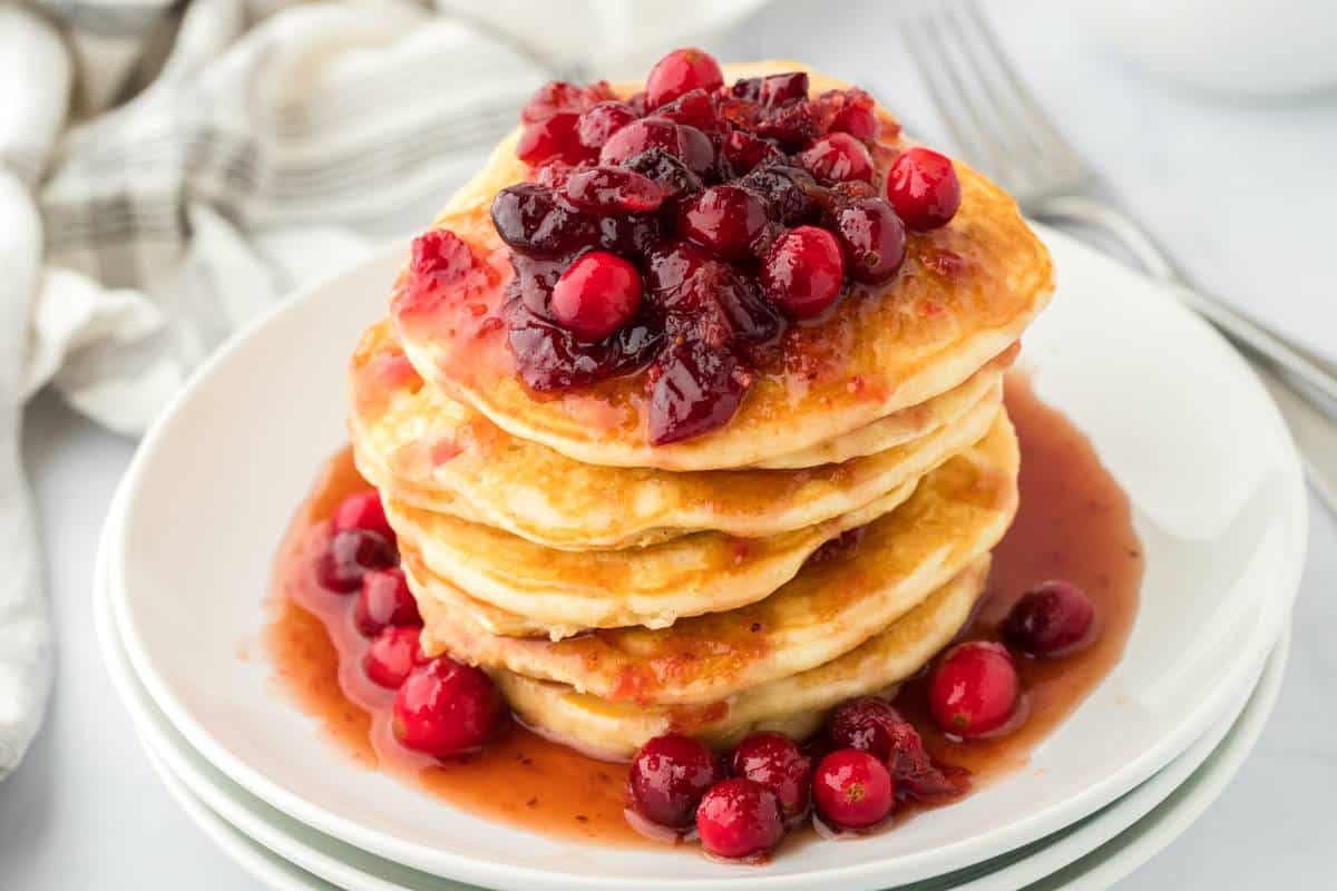 A stack of eggnog pancakes topped with a homemade cranberry syrup on top.