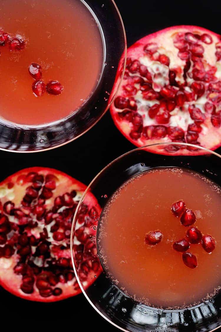 Overhead shot of two glasses of Pomegranate Orange Champagne Cocktail topped with pomegranate seeds