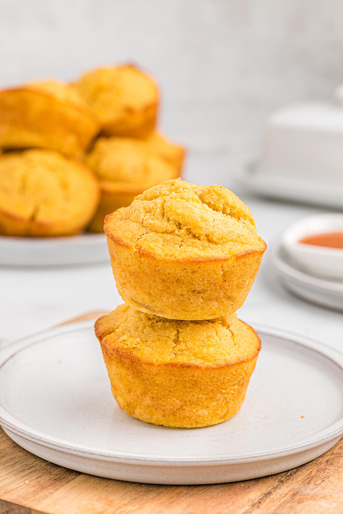 Two sweet potato cornbread muffins stacked on top of each other on a plate.