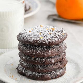 Flourless Chocolate cookies in a stack on a white plate on gray background