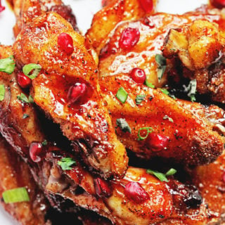 Pomegranate chicken wings piled up on a white plate