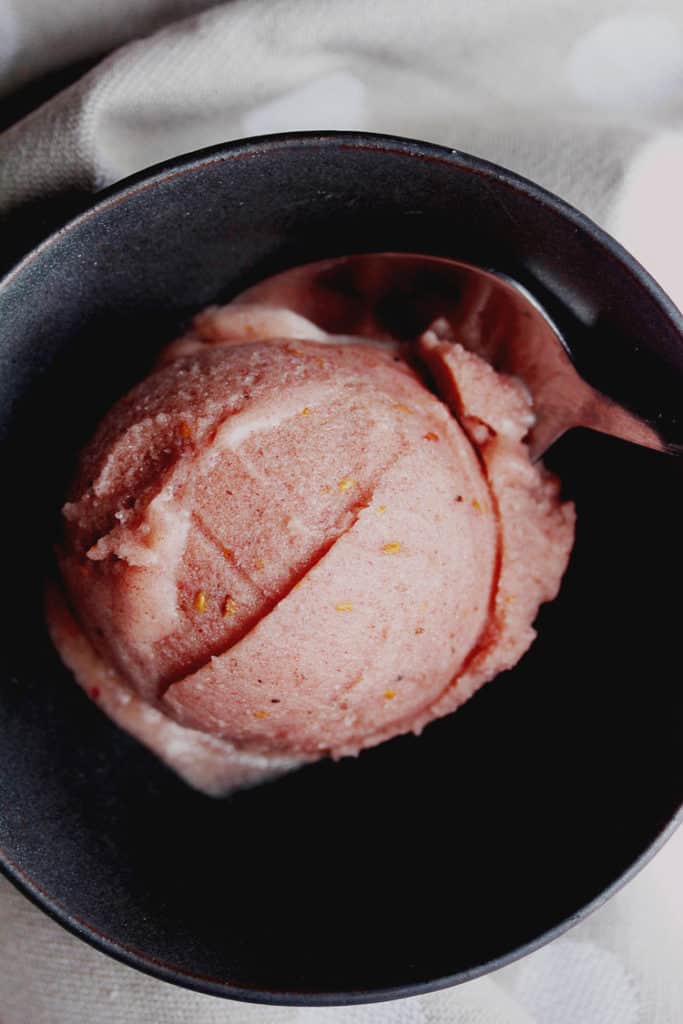 Close up of one scoop of raspberry banana nice cream in a bowl with a spoon in it