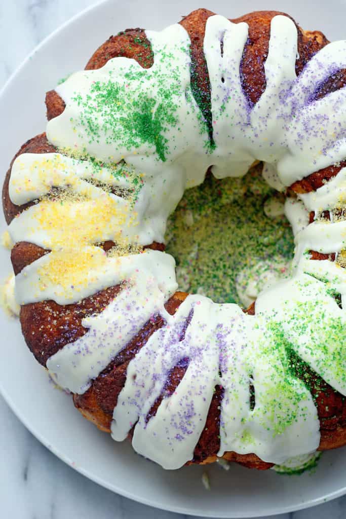 Mardi Gras King Cake topped with cream cheese icing and purple, yellow and green sanding sugar. 
