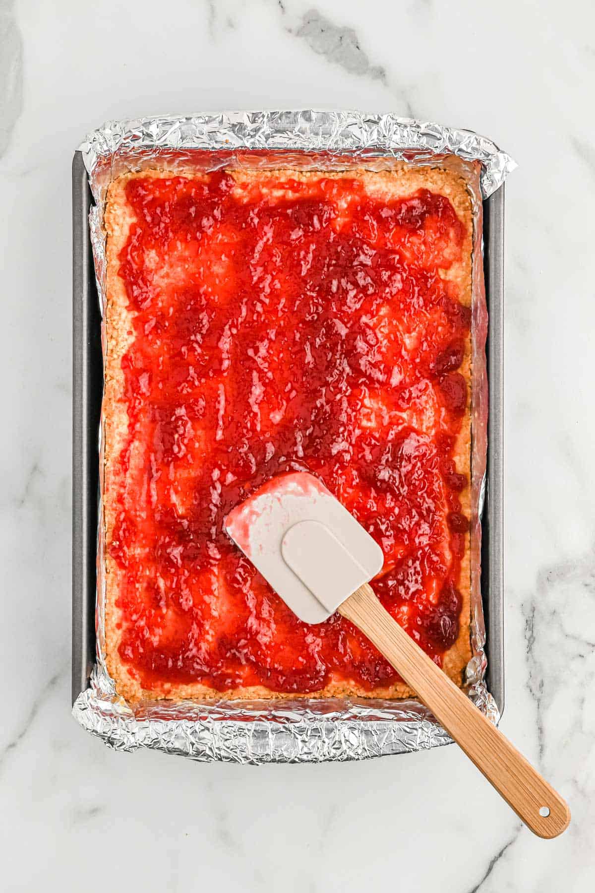 Raspberry jam spread over the top of the crust.