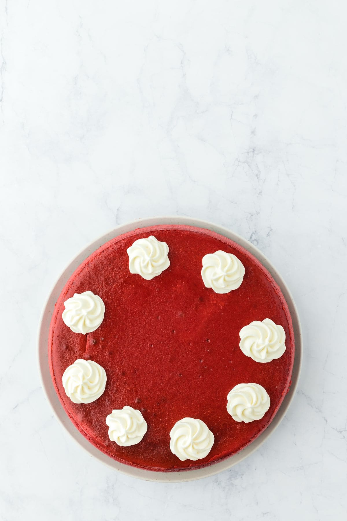 Whipped cream rosettes piped onto the top of a red velvet cheesecake.