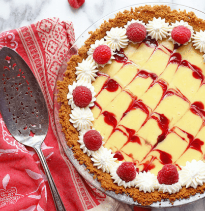 Overhead shot of a raspberry key lime pie topped with whipped cream and fresh raspberries