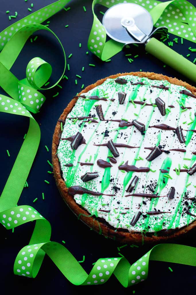 St. Patrick's Day Dessert Pizza surrounded by green streamers, green sprinkles and a pizza cutter