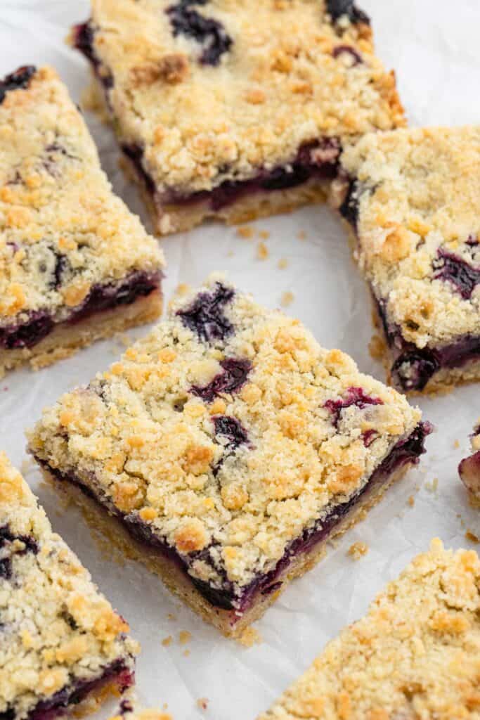 Several blueberry crumble bars are cut in squares with blueberries as garnish