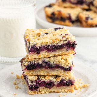Blueberry Crumble Bars stacked on a white plate on a white background