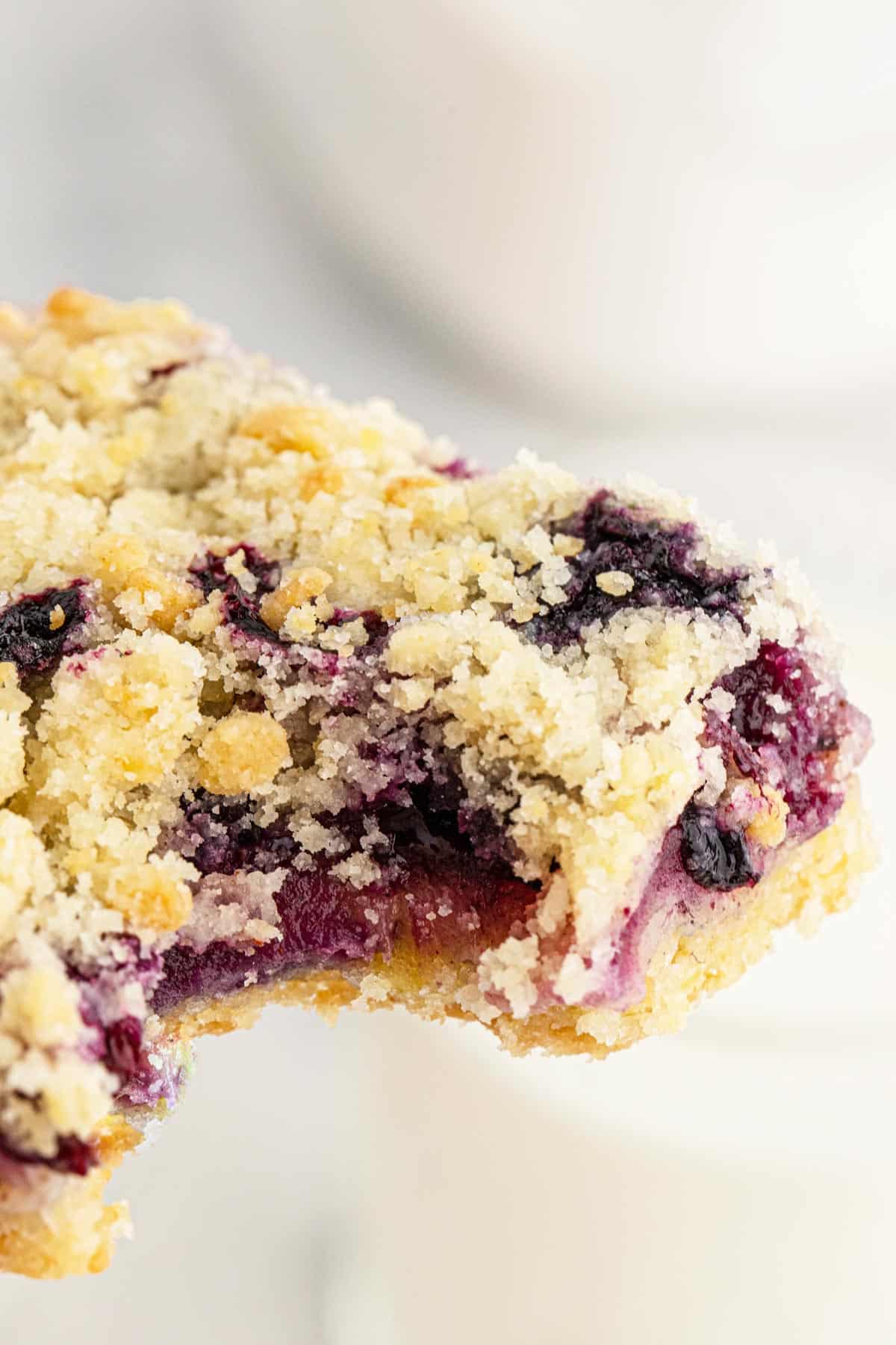 A close up of one crumble blueberry bar with a bite missing.