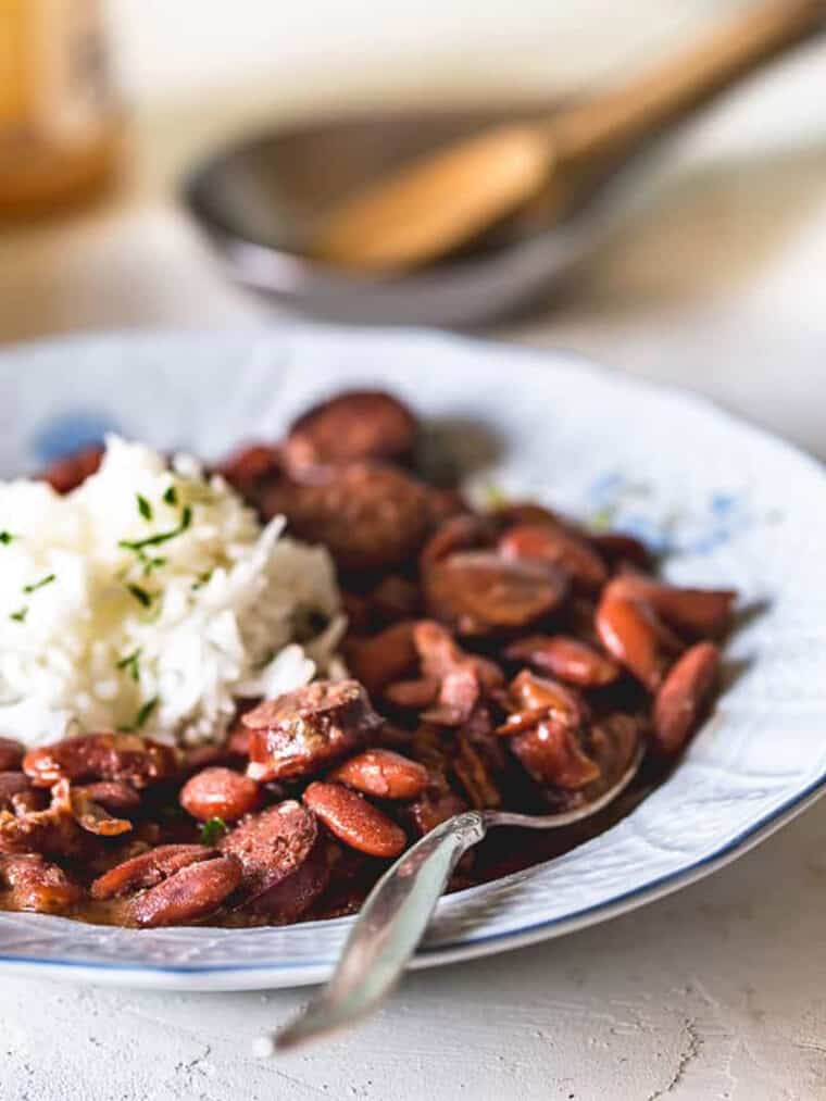 A plate of cajun red beans and rice on the table with a spoon in the bowl.