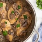 Closeup overhead shot of chicken marsala recipe with mushrooms and parsley in a pan, with fresh pasta and parsley nearby
