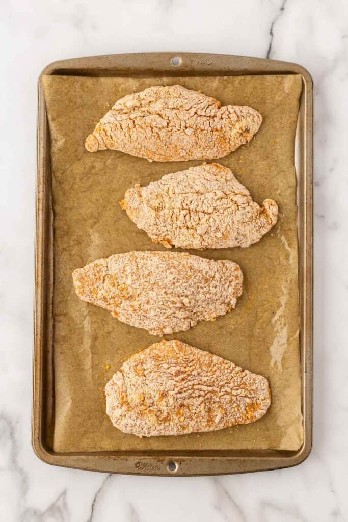 Breaded fish on greased parchment paper