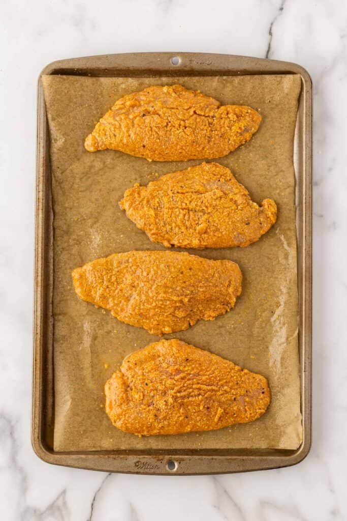 Sprayed breaded fish on a parchment lined baking sheet
