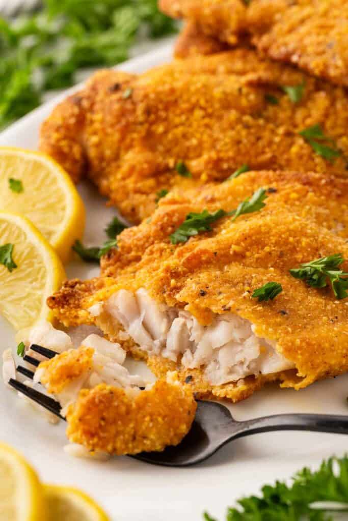 Tender flaky oven fried fish being cut open