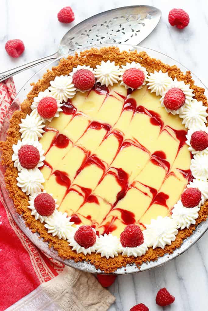 Close up of easy key lime pie recipe garnished with raspberries and whipped cream.