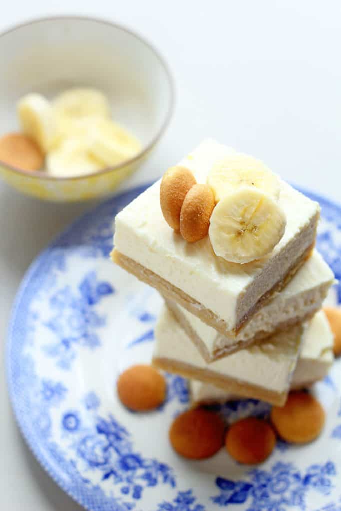 An overhead of a stack of banana pudding cheesecake bars over blue and white plate ready to serve